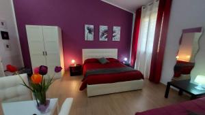 Schlafzimmer mit einem roten Bett und lila Wänden in der Unterkunft La Suite Di Segesta in Calatafimi