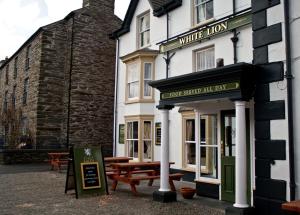 a white inn with picnic tables in front of it at The White Lion Hotel in Machynlleth