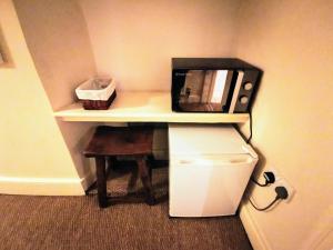a small kitchen with a refrigerator, microwave and bookshelf at The Darlington in Camelford