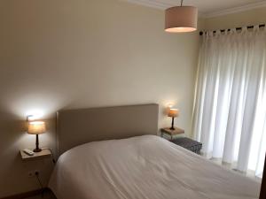 a bedroom with a bed and two lamps on tables at Apartamentos Pomba Branca in Olhos de Água +11 photos