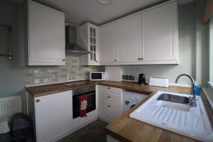 Una cocina con gabinetes blancos y un fregadero. en Somerset House, en Sheffield 26 fotos más