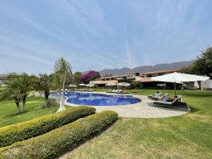 un complejo con una piscina con personas sentadas sobre sillas y sombrillas en La Reserva Chapala en Ajijic