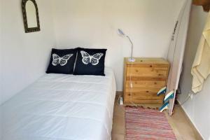 una camera da letto con un letto con farfalle sui cuscini di Casinha de Aldeia no coração da Costa Vicentina a Vila do Bispo