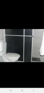 a bathroom with a white toilet and a black wall at Magias da Serra in Canela