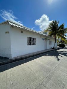 a white building with a palm tree in front of it at Posada Yasa sarie bay in San Andrés