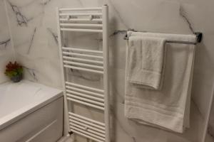 ein weißes Bad mit weißen Handtüchern auf einem Handtuchhalter in der Unterkunft Serene Apartment Navodari in Năvodari