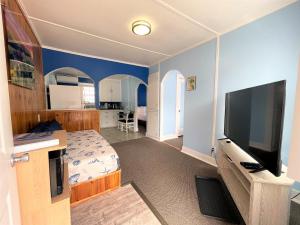 1 dormitorio con 1 cama y TV de pantalla plana en The Anchorage Motel, en Pacific City