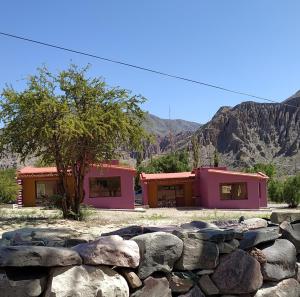 ein paar rosa Gebäude mit einer Felswand in der Unterkunft Pirca del Abuelo II in Purmamarca