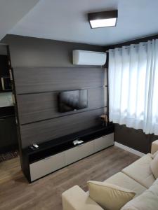 uma sala de estar com um sofá e uma televisão de ecrã plano em Apartamento no Residencial Vert em Bento Gonçalves-RS em Bento Gonçalves