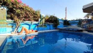 Eine Frau, die am Rande eines Schwimmbads liegt. in der Unterkunft Luxor Guest House in Luxor