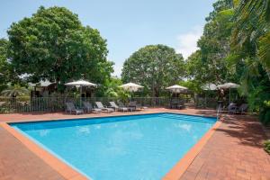 - une piscine avec des chaises longues et des parasols dans l'établissement Mantra Frangipani Broome, à Broome