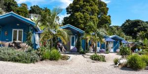 uma casa azul com palmeiras em frente em Boatsheds on the Bay, Waiheke Island em Ostend