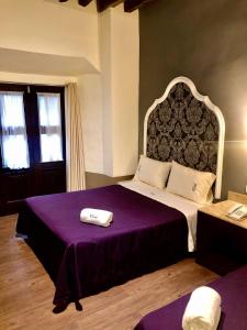 a bedroom with a large bed with a purple blanket at Hotel Gala in Puebla