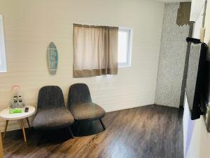 a room with two chairs and a table and a surfboard at King Wow Inn in Tainan