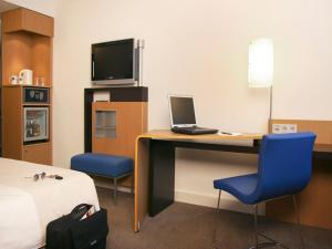 Zimmer mit einem Schreibtisch mit einem Laptop und blauen Stühlen. in der Unterkunft Novotel Nürnberg am Messezentrum in Nürnberg
