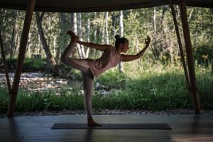 a woman doing a yoga pose on a yoga mat at Bodhi Farms in Bozeman