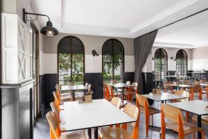 a dining room with tables and chairs and windows at Mantra on Jolimont in Melbourne