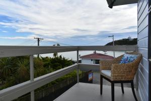 a chair on a balcony with a view of the ocean at Moeraki Beach Motels in Moeraki