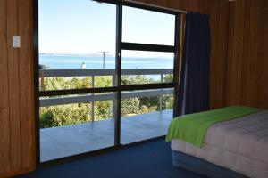 a bedroom with a large glass door with a view of the ocean at Moeraki Beach Motels in Moeraki