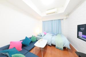 a living room with a blue couch with colorful pillows at IBASHO ShibuyaDogenzaka907 in Tokyo