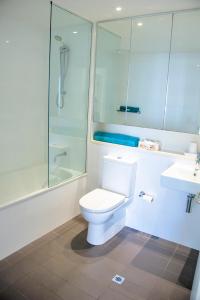 a bathroom with a toilet and a shower and a sink at Absolute Waterfront - Tropical Aurora Top Floor Over The Water in Darwin
