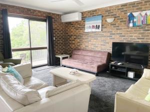 a living room with two couches and a tv at Sands Court on Boyd, Top floor 2 bedroom unit, seconds from the beach! in Woorim