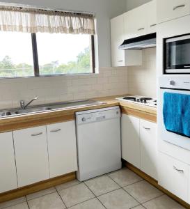 a kitchen with white cabinets and a sink at Sands Court on Boyd, Top floor 2 bedroom unit, seconds from the beach! in Woorim