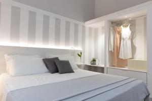 a white bedroom with a white bed and a dress rack at Midenza Seaside & Nature Retreat in Capo Vaticano