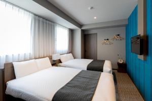 a hotel room with two beds and a television at BON Kyoto Kiyomizu in Kyoto
