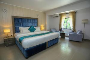 Riviera Suites في لاغوس: غرفة نوم كبيرة مع سرير كبير وكرسي