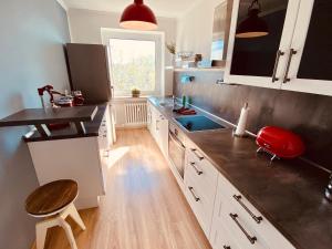 a kitchen with white cabinets and a red stool at COAST HOUSE River Docks in Bremerhaven