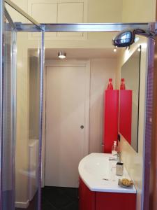 La salle de bains est pourvue d'un lavabo rouge et d'une douche. dans l'établissement La Piazzetta, à Stresa