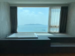 巨济Hotel SANG SANG & Private SANG SANG POOL VILLA的一间位于大窗户前的带浴缸的浴室