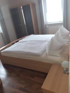 a bed with white sheets and pillows in a room at Ferienwohnungen Bernd Krügel in Zwickau