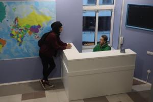 a woman standing at a counter in a room with a mirror at If Hostel in Lviv