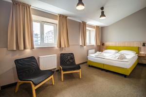 ein Schlafzimmer mit einem Bett und zwei Stühlen darin in der Unterkunft Corner Hotel in Vilnius