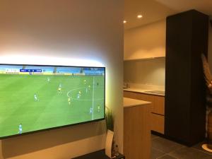 a television hanging on a wall with a soccer game at BLOC79/TWO in Knokke-Heist
