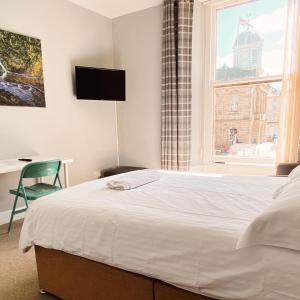 a bedroom with a white bed and a window at Studio Apartments on the Square in Kelso