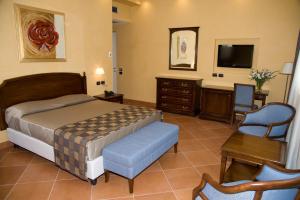 a bedroom with a bed and a desk and a tv at Artemis Hotel in Cefalù