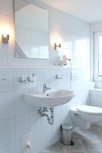 La salle de bains blanche est pourvue d'un lavabo et de toilettes. dans l'établissement Flippi-s-Hues-WEST, à Westerland