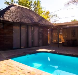 a house with a swimming pool in front of a building at Oppi Draai Guesthouse in Oudtshoorn