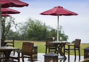 a patio with tables and chairs with an umbrella at The Tamara Kodai in Kodaikānāl
