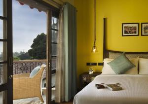 a hotel room with a bed and a balcony at The Tamara Kodai in Kodaikānāl