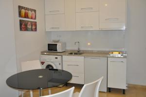 cocina con mesa negra y armarios blancos en Valencia City Center New Apartments, en Valencia