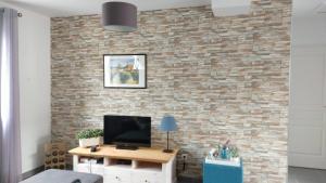 a living room with a brick wall with a television at La Cigale - Pte des Gorges - Piscine privée chauffée in Vallon-Pont-dʼArc