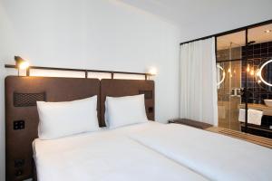 a bedroom with a white bed and a large window at H2 Hotel Budapest in Budapest