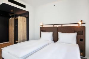 two beds in a room with white sheets at H2 Hotel Budapest in Budapest