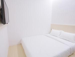 a white bed with white pillows and a tv at Minimalist Hotel in Johor Bahru