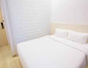 ジョホールバルにあるMinimalist Hotelの白いベッド(白いシーツ、枕付)
