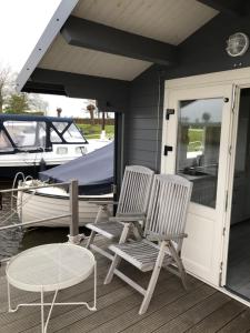 two chairs and a table on a porch with a boat at Waterhut 2 Aduarderzijl in Feerwerd